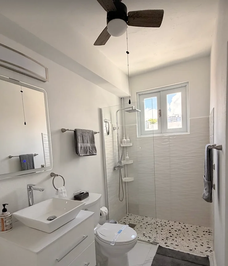Baño de un Airbnb listo para recibir huéspedes, con ducha de cristal y toallas acomodadas