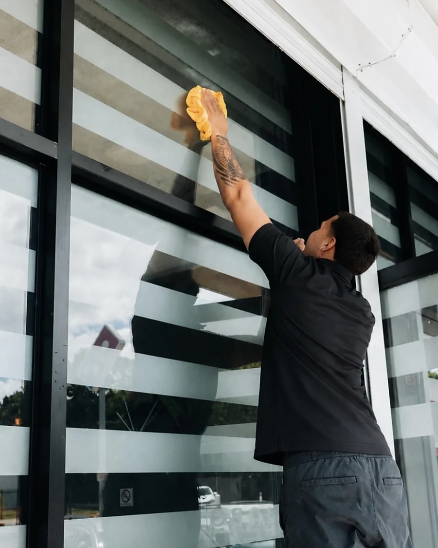Empleado de Clean Vibes limpiando los cristales de la fachada de un local comercial