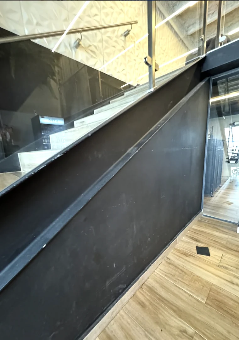 Detalle de baranda de cristal y piso de madera de un espacio comercial